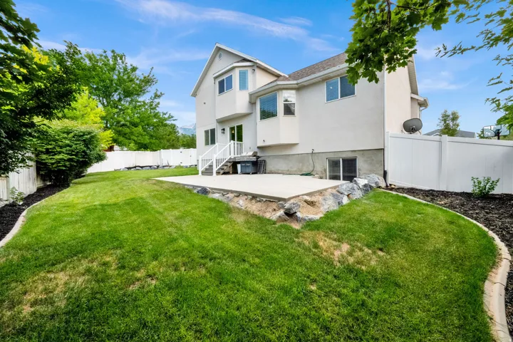 Rear exterior featuring a concrete patio, a walk-out basement entrance, and a terraced lawn area