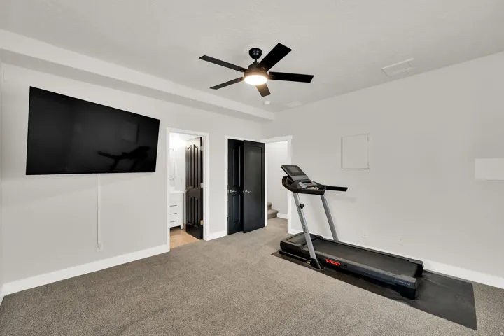 Spacious room featuring high end neutral carpeting, 9' ceiling ,a ceiling fan, and a wall-mounted display