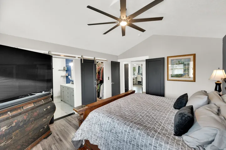 Vaulted ceiling bedroom featuring upgraded  flooring and a modern ceiling fan