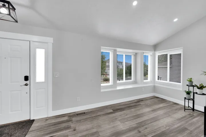 Entry area featuring upgraded NuCore performance ridged-core LVP flooring,, vaulted ceilings with recessed lighting, and a front door with an integrated sidelight