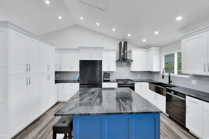 Bright kitchen featuring a vaulted ceiling with recessed lighting