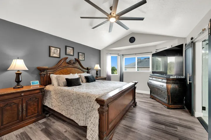 Vaulted ceiling bedroom featuring upgraded  flooring and a ceiling fan
