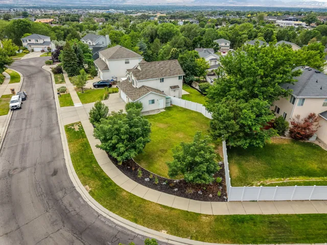 Spacious corner lot featuring a verdant lawn, mature trees, and a white privacy fence
