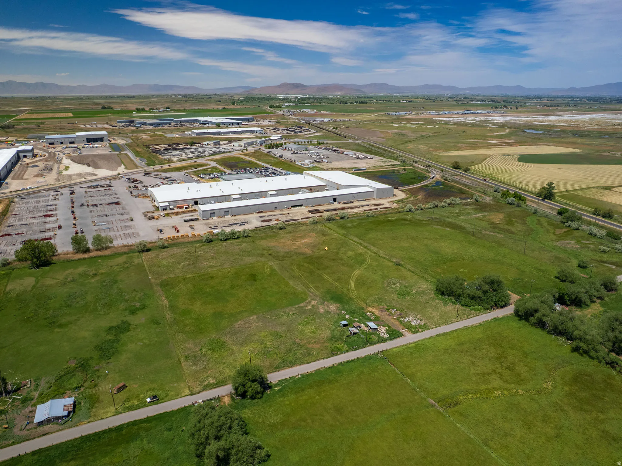 Aerial perspective showcasing extensive commercial properties featuring large industrial buildings with white roofs and substantial paved parking areas