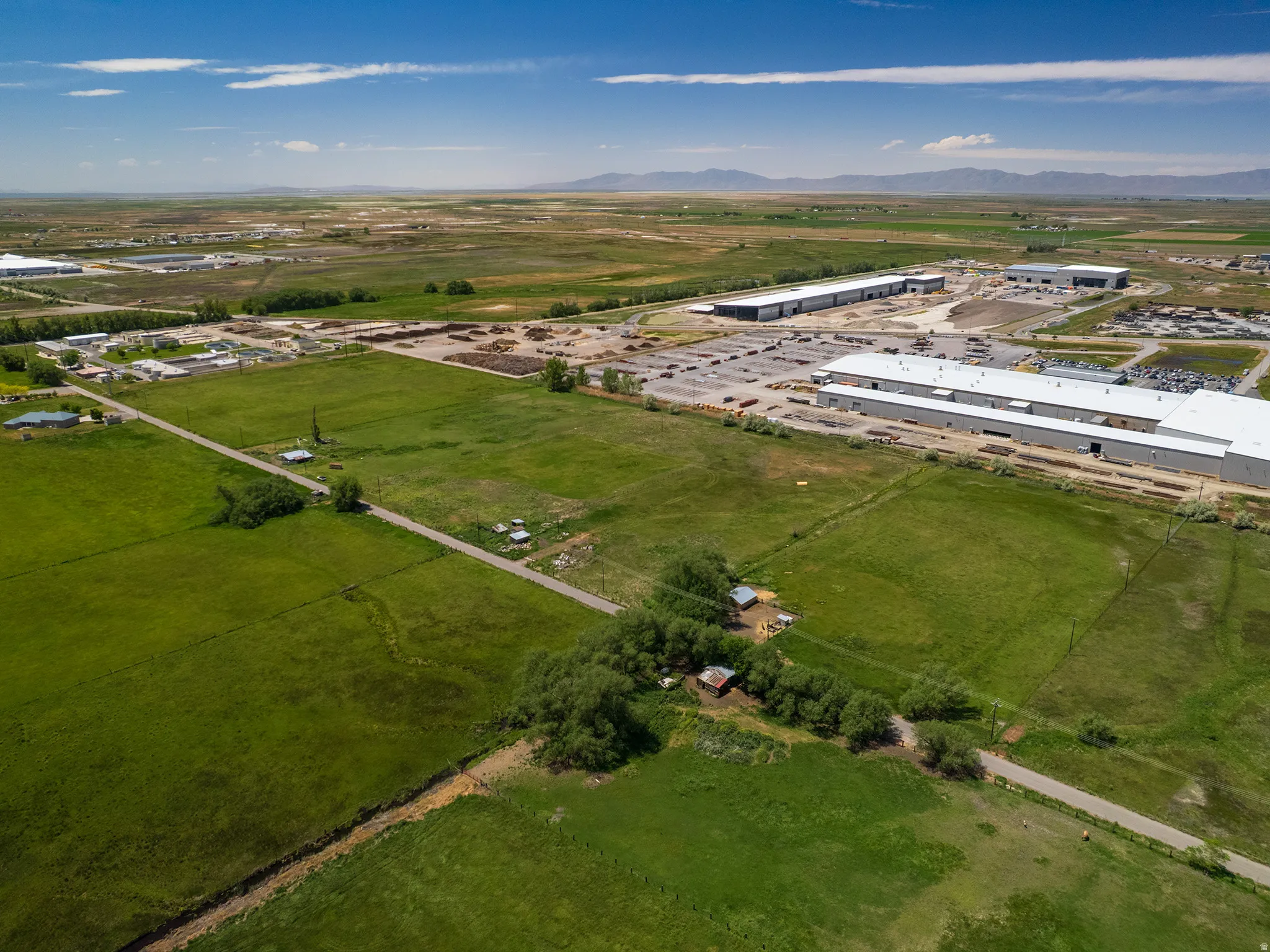 Expansive green fields featuring clear boundaries and distant industrial buildings