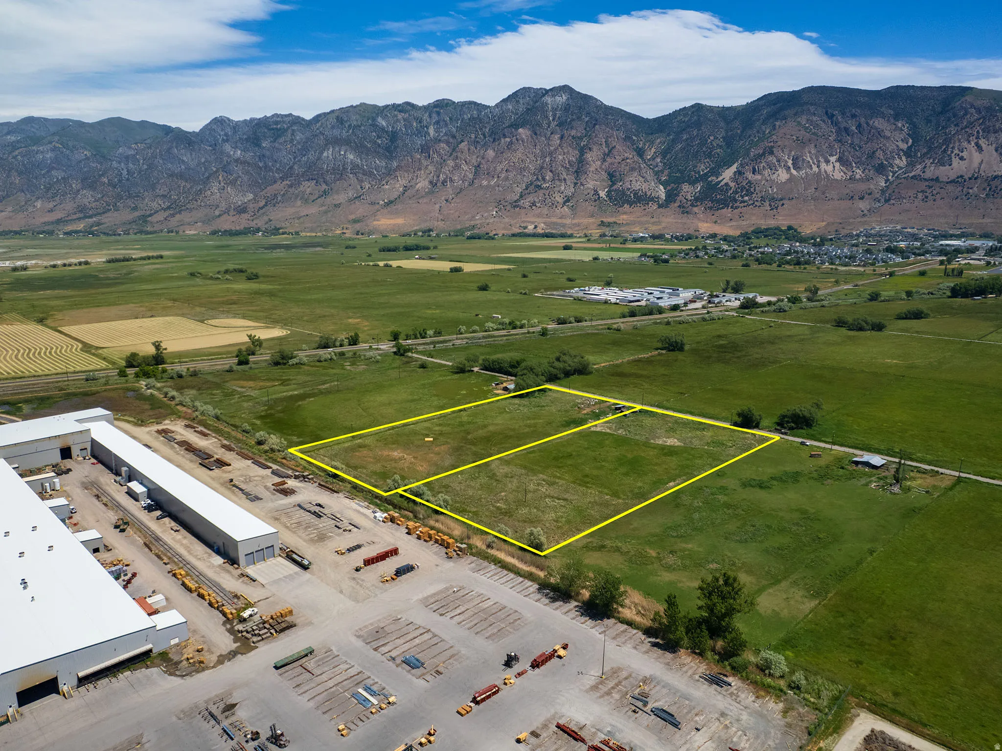 Expansive undeveloped land parcels with agricultural surroundings, featuring a distant mountain backdrop and  epansive green space marked in yelow boundary line featuring three  parcels including Parcel # 03-077-0015, and adjacent parcel available for sal
