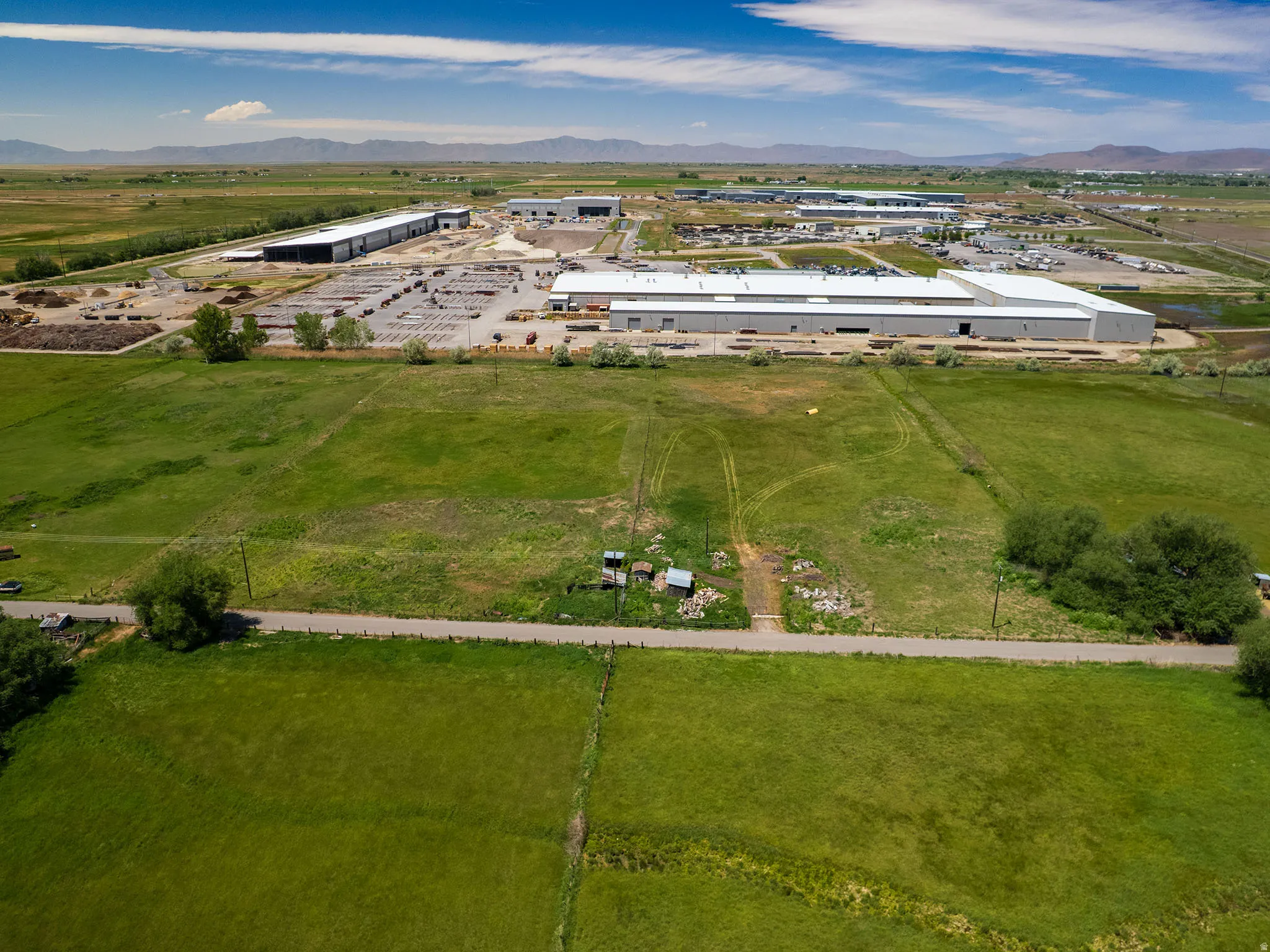 Expansive industrial property featuring multiple large buildings with light-colored roofing and substantial open-air storage/parking areas