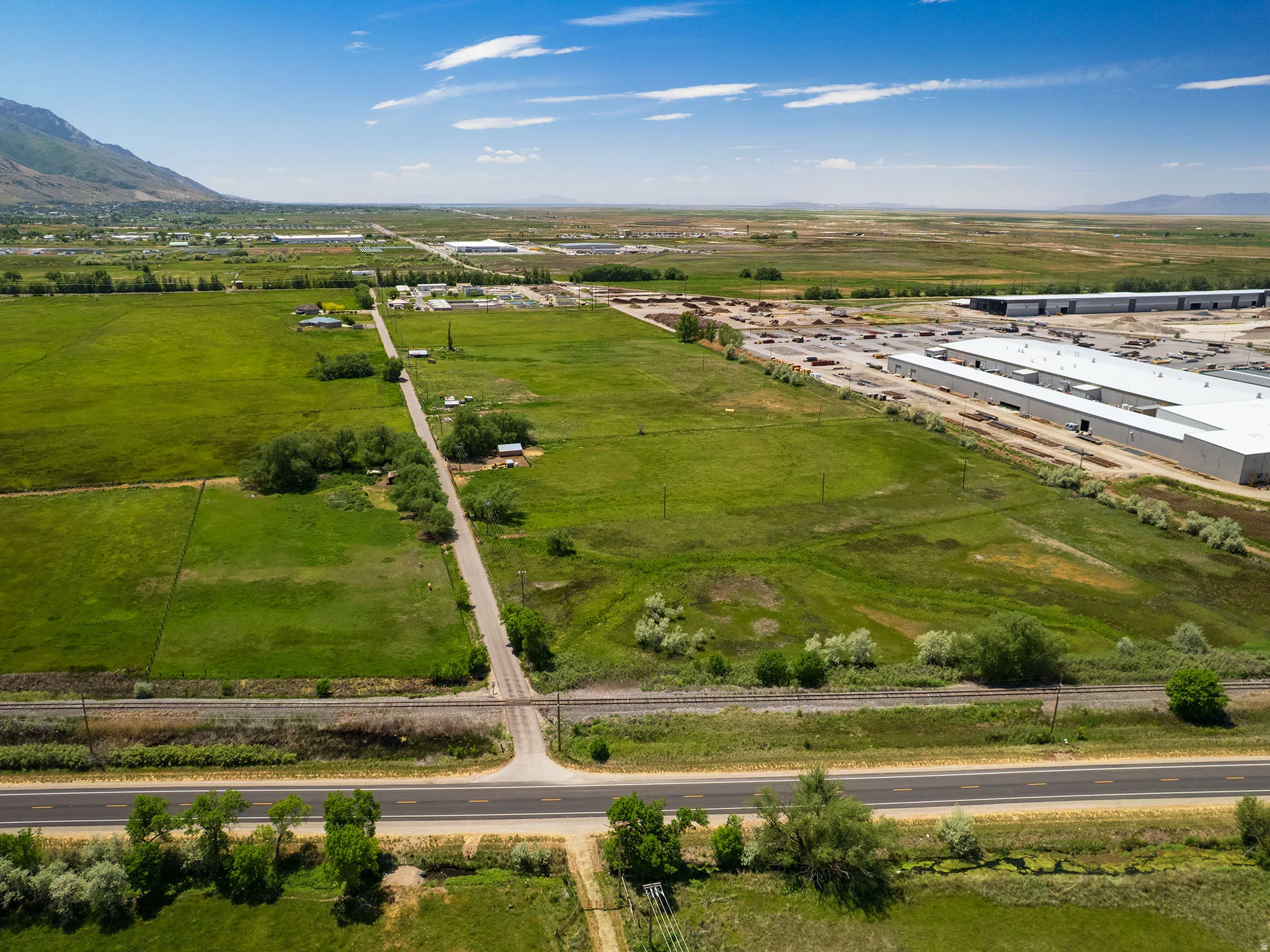 Expansive green acreage with a paved roadway and rail line traversing the property