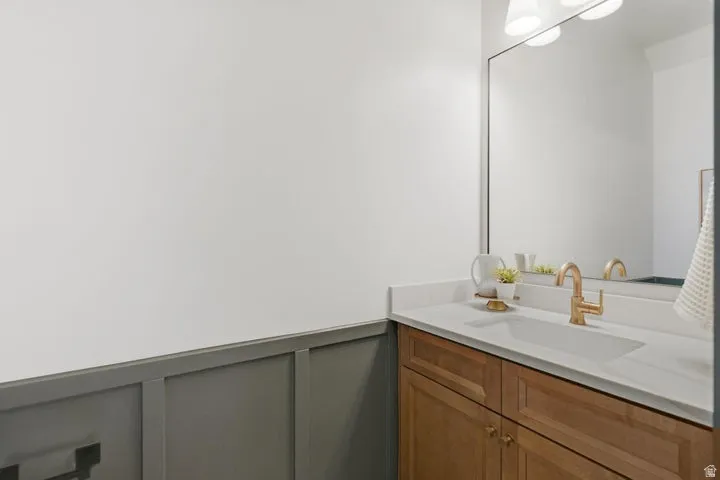 Single vanity with a light wood-finish cabinet and brass hardware