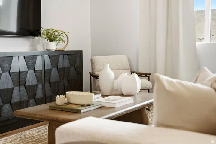 Living area featuring a geometric pattern console, wood-finish flooring, and white window treatments