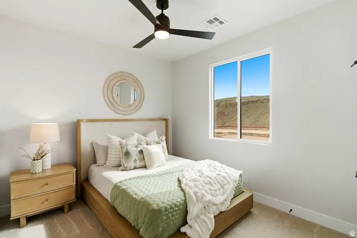 Bright room featuring a single window, a dark ceiling fan with integrated lighting, light-colored walls, and neutral-toned carpeting