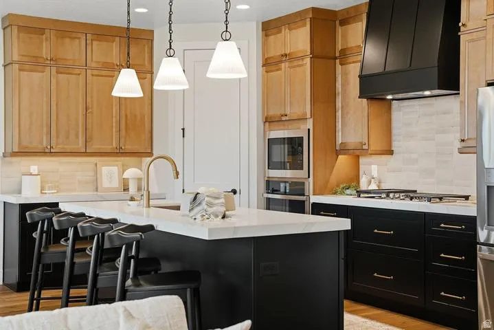 Kitchen featuring a large island with white countertop, brass-finish faucet, and three pendant lights
