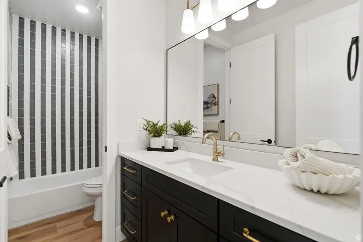 Modern vanity featuring a white countertop with integrated sink, gold-finish faucet, and black cabinetry with gold-tone hardware