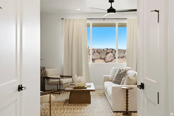 Living area featuring a large window, a modern ceiling fan, and light-toned walls