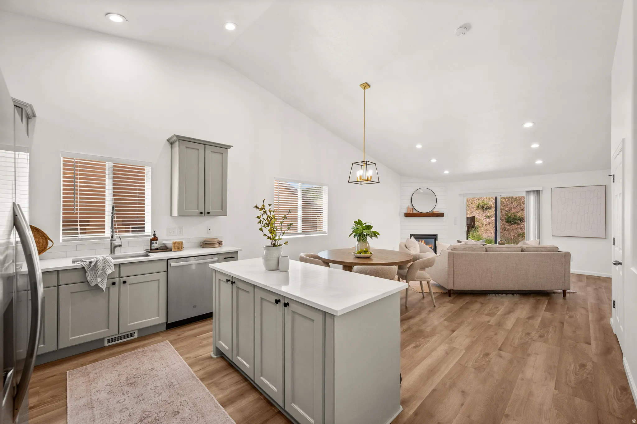 Open-concept living space featuring wood-finish flooring, vaulted ceilings, and recessed lighting