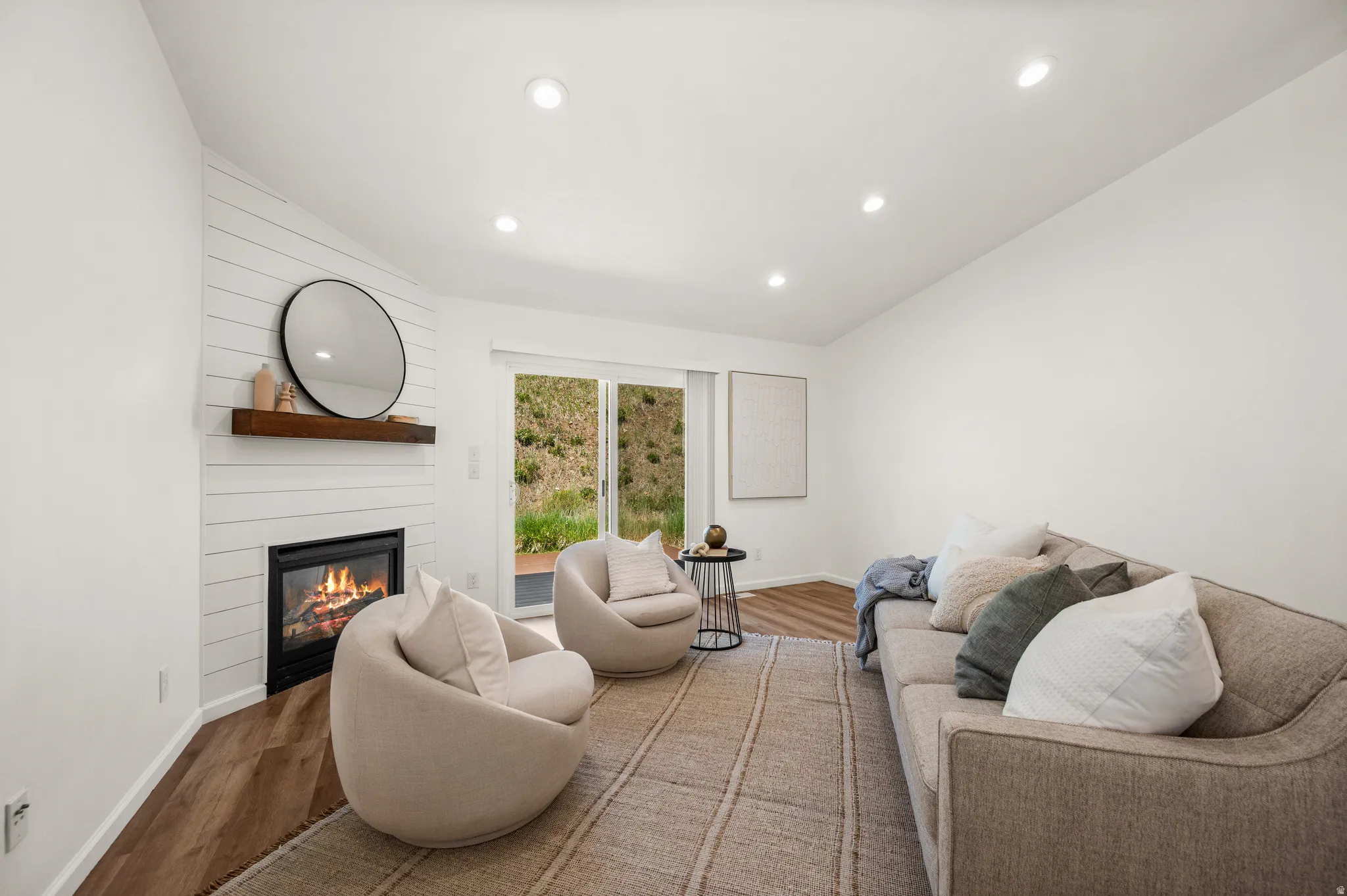 Living area featuring a modern fireplace with a shiplap surround, a wood mantel, and recessed lighting