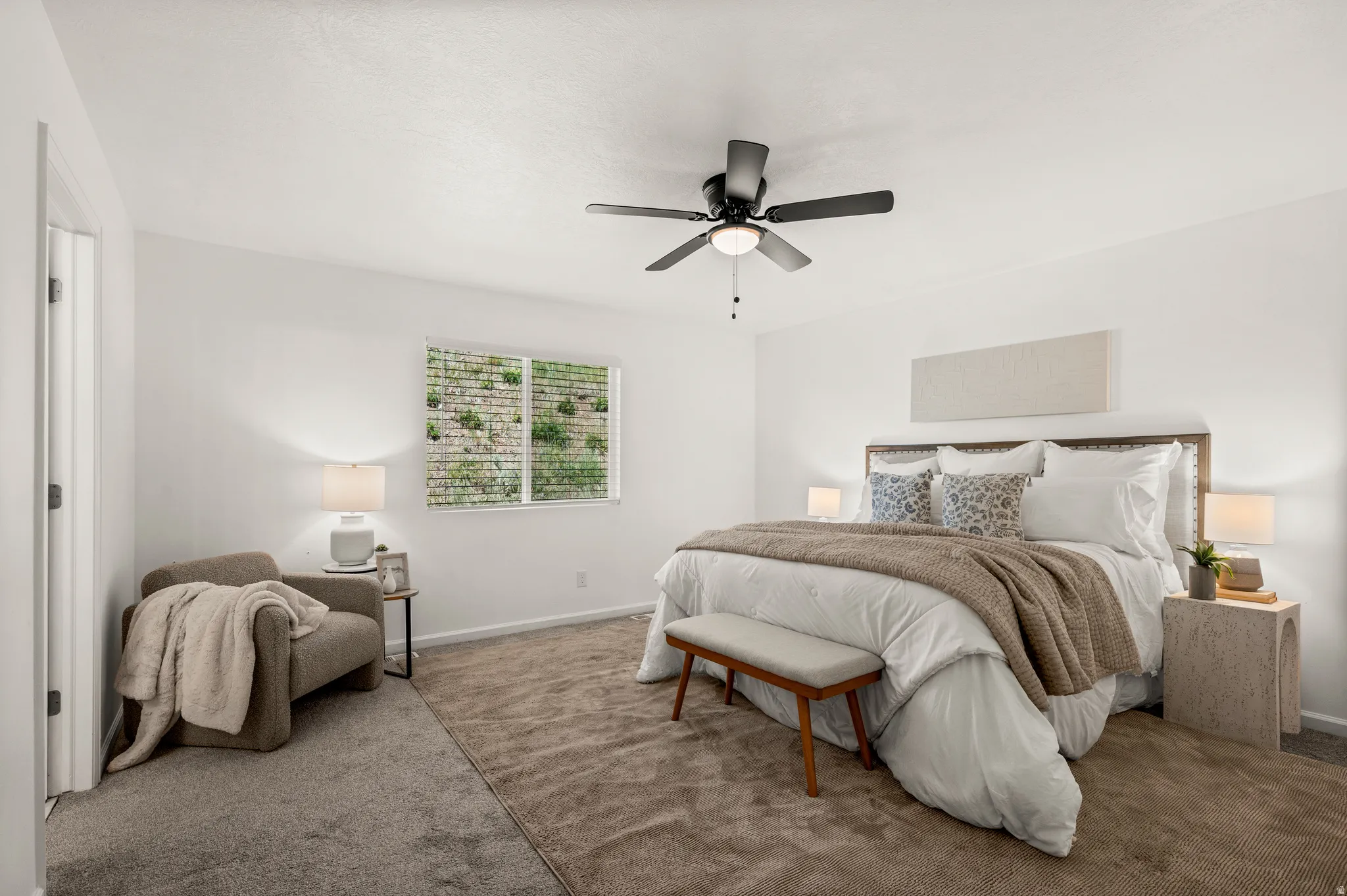 Bright bedroom featuring a single window, a ceiling fan with integrated lighting, and neutral tone carpeting