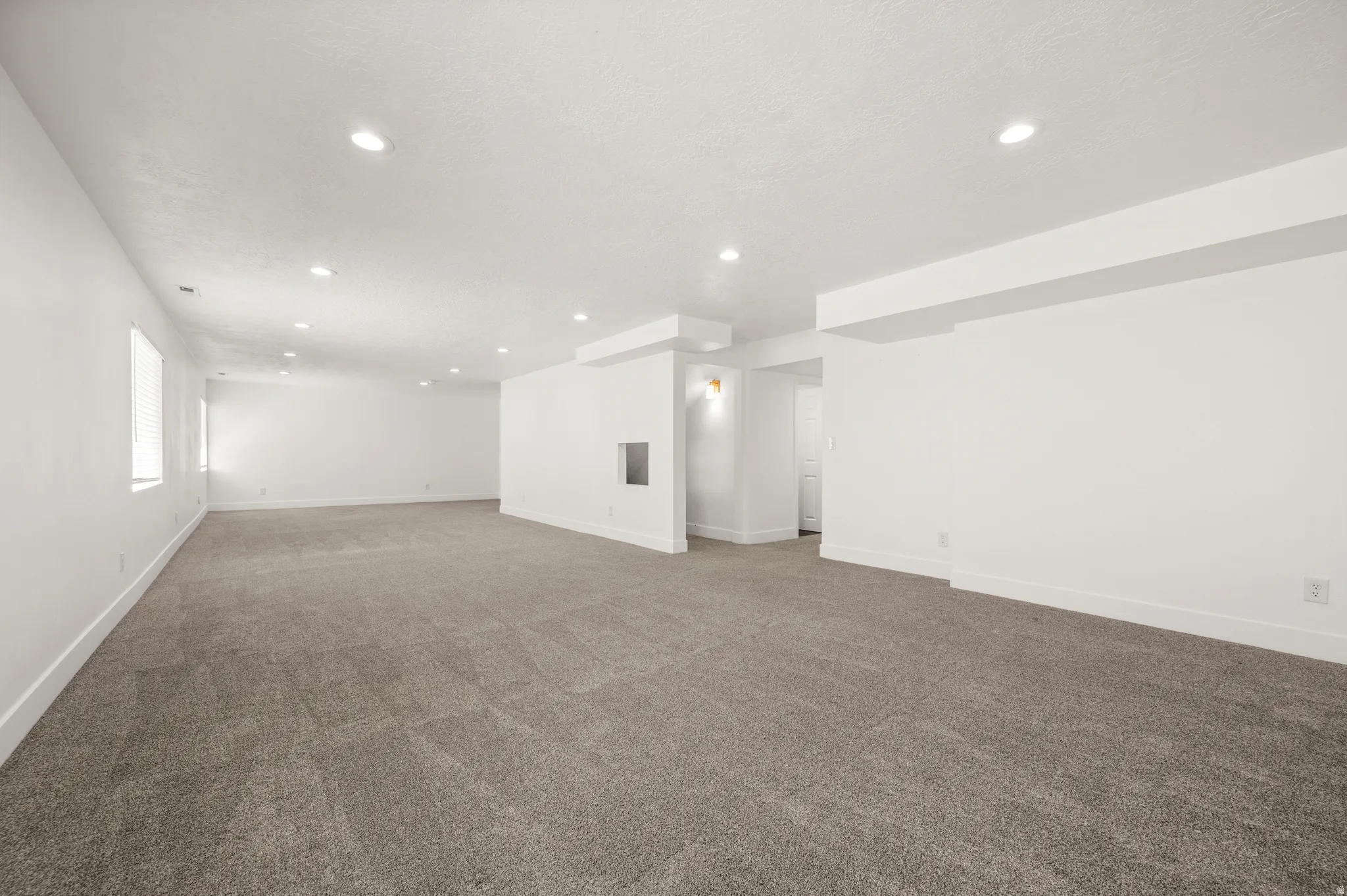 Spacious room featuring gray carpet, recessed lighting, white walls, and multiple windows