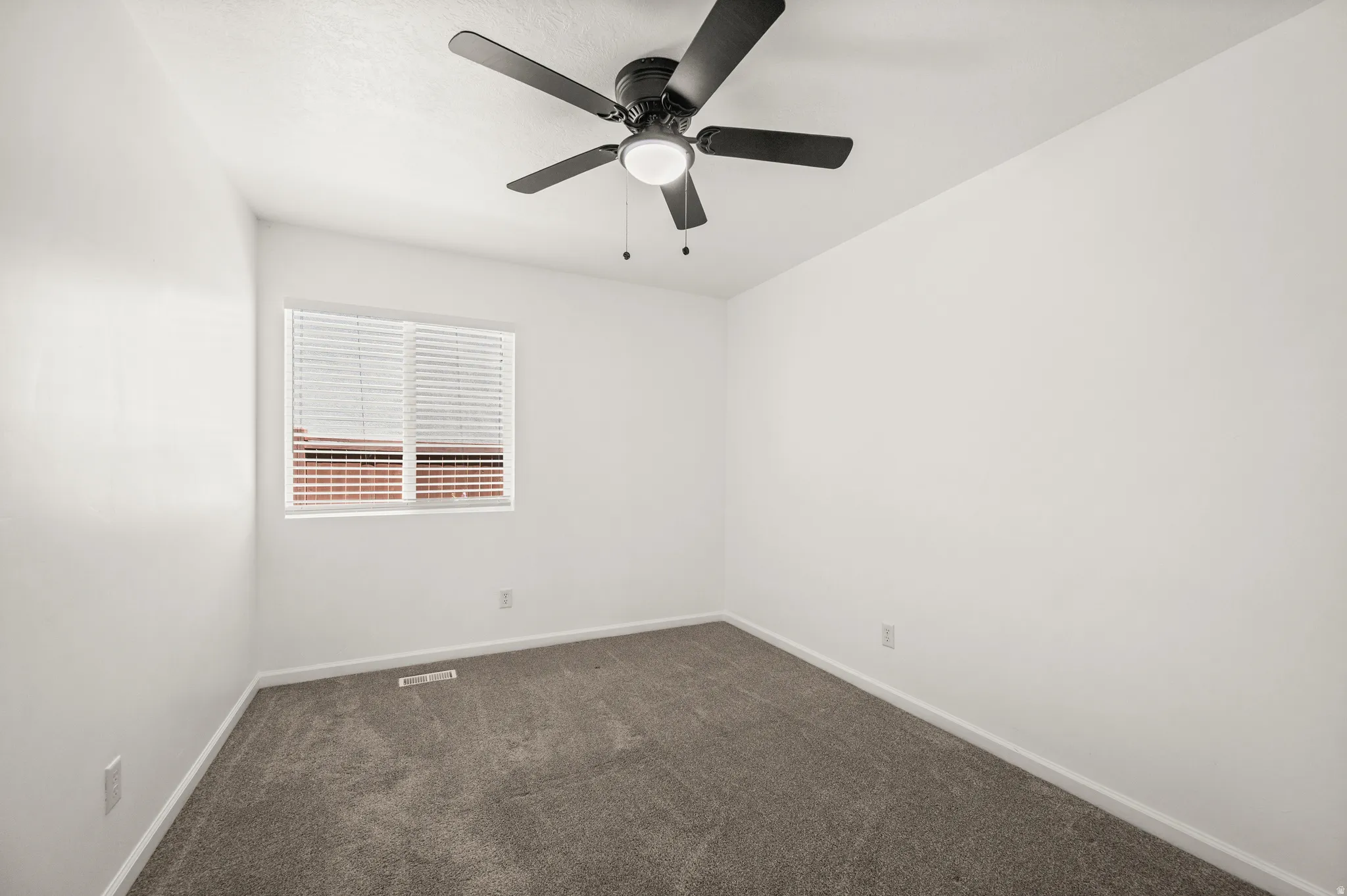 Room featuring a ceiling fan with integrated lighting, a window with horizontal blinds, neutral wall paint, and gray carpet flooring