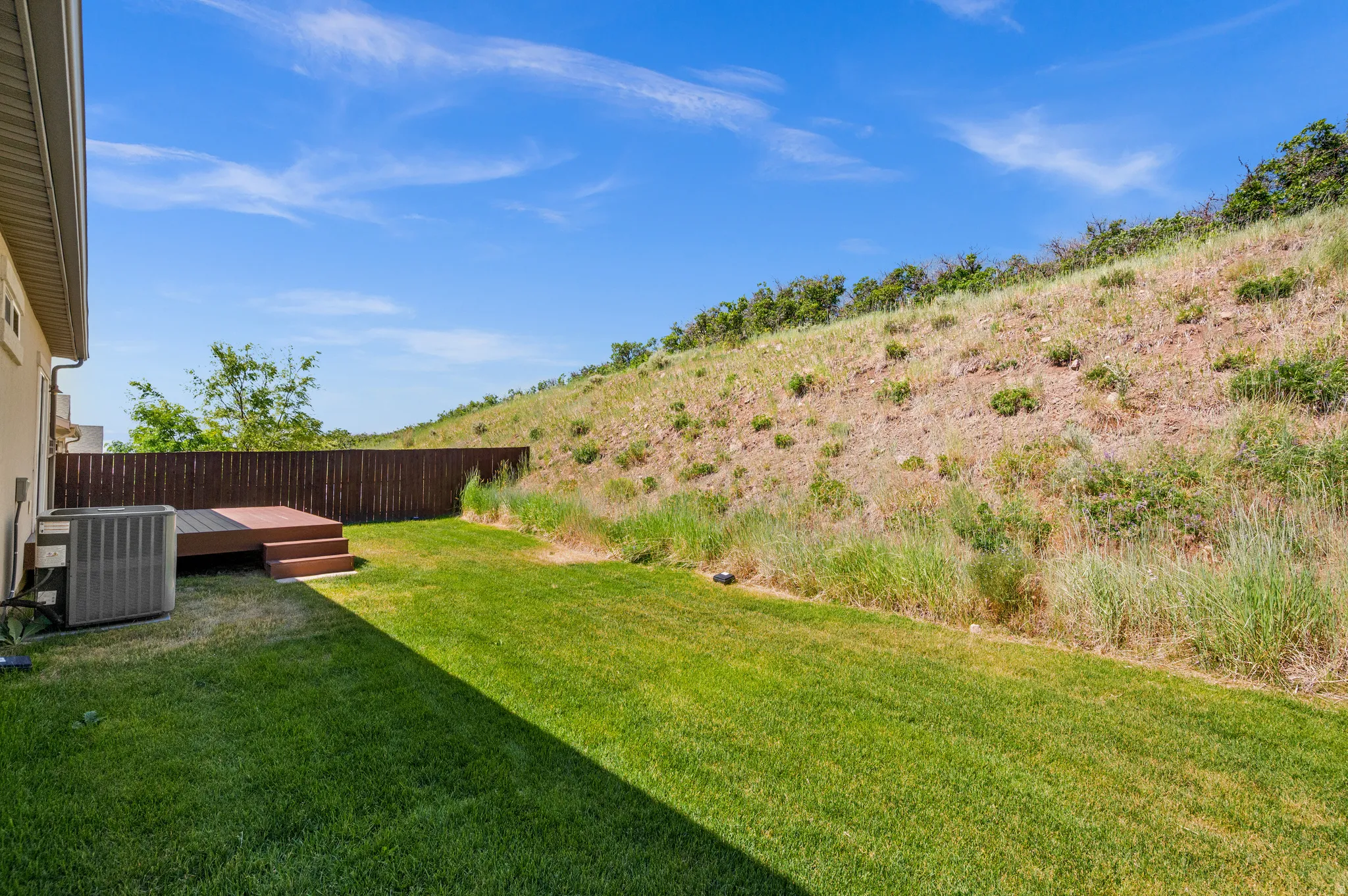 Expansive rear yard featuring a manicured lawn, multi-level composite decking, and a privacy fence