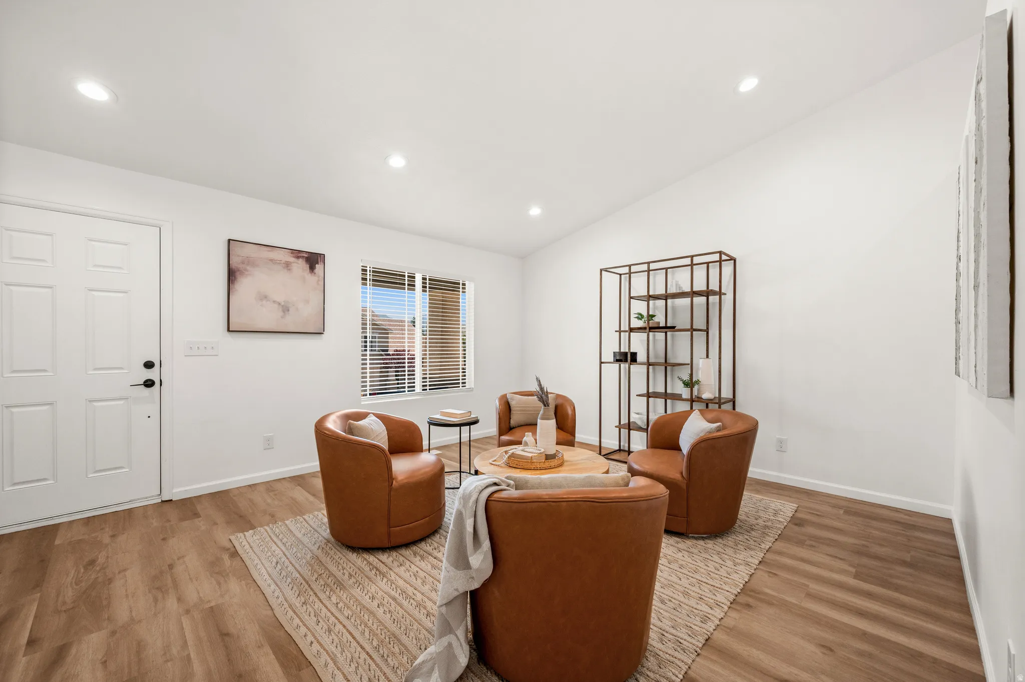 Spacious interior room featuring wood-finish flooring, recessed lighting, and a white paneled entry door