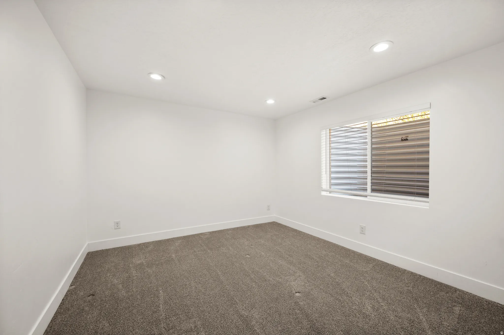 Room featuring white walls, recessed ceiling lighting, and gray carpeting