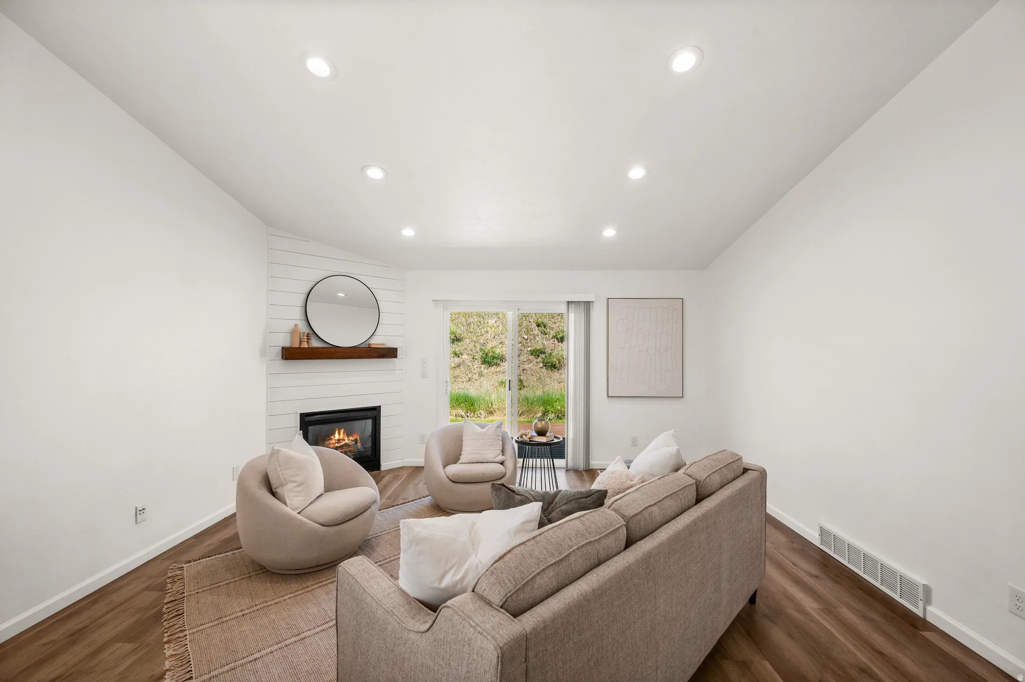 Living area featuring wood-finish flooring, recessed lighting, and a corner fireplace with a shiplap accent wall and wood mantel