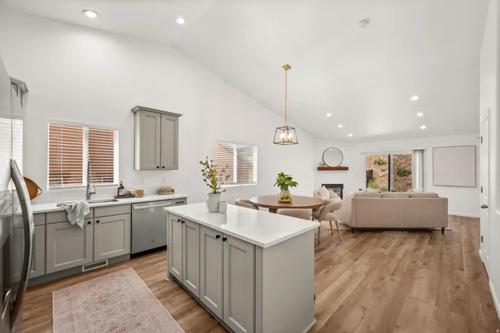 Open-concept living space featuring wood-finish flooring, vaulted ceilings, and recessed lighting