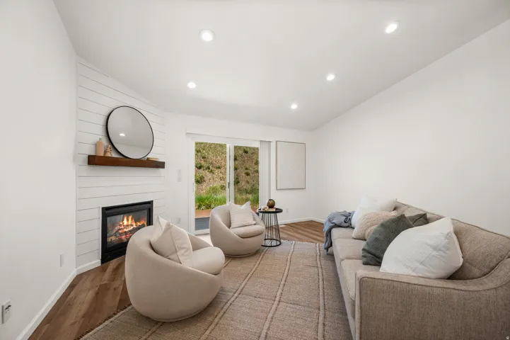 Living area featuring a modern fireplace with a shiplap surround, a wood mantel, and recessed lighting