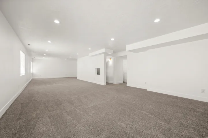 Spacious room featuring gray carpet, recessed lighting, white walls, and multiple windows