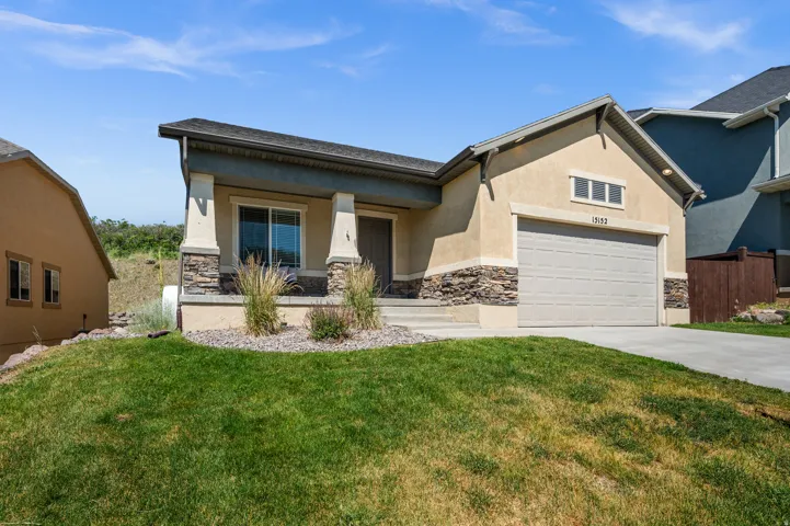 Front exterior featuring a stucco finish with stone veneer accents, a covered porch with square columns, a two-car garage, and a concrete driveway