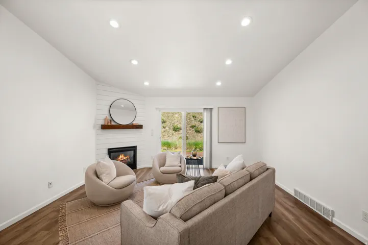 Living area featuring wood-finish flooring, recessed lighting, and a corner fireplace with a shiplap accent wall and wood mantel
