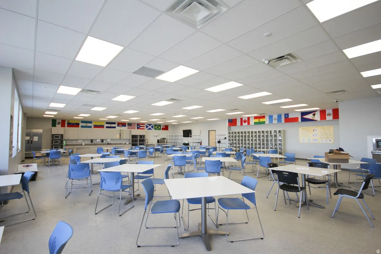 Spacious interior featuring a grid ceiling with integrated lighting, light-toned flooring, and a bank of windows