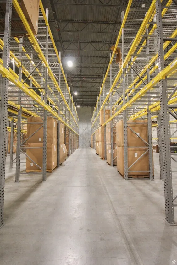 Warehouse interior featuring high ceilings, extensive metal racking systems, concrete flooring, and overhead lighting