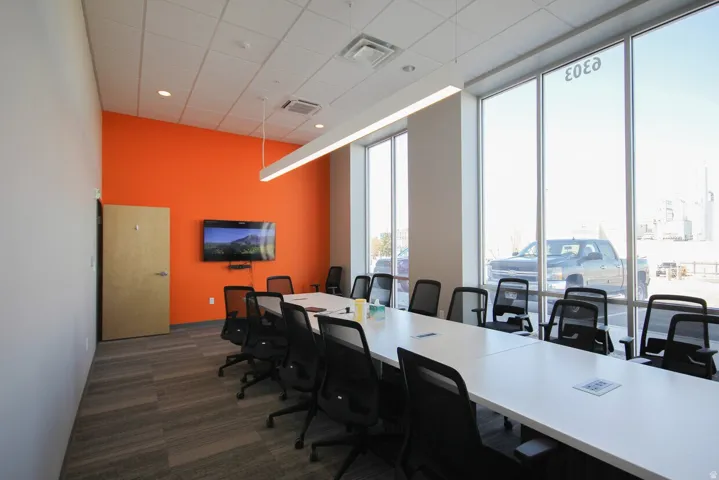 Conference room featuring a vibrant accent wall, expansive windows, recessed lighting, and a mounted display