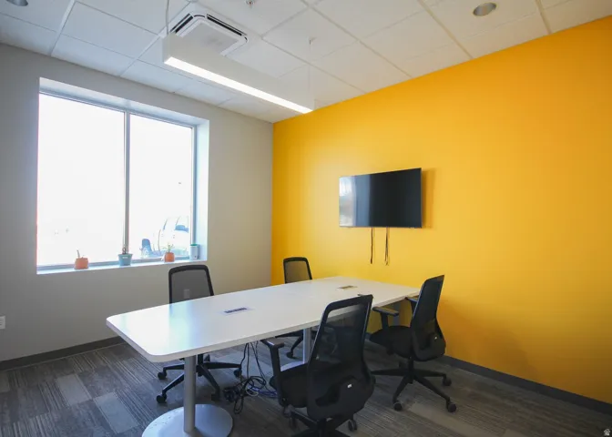 Meeting space featuring a bright accent wall and a large window