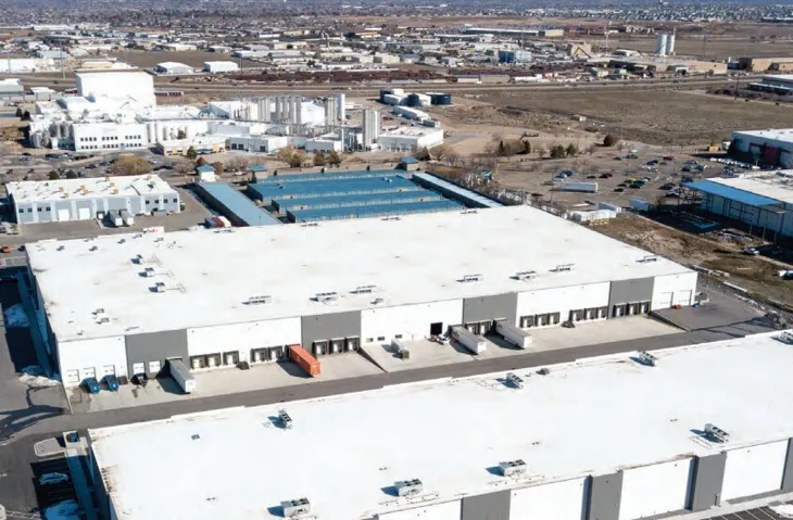 Industrial property featuring a large white roof, multiple loading docks, and ample exterior space for vehicle access