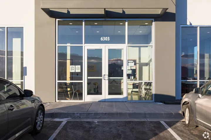 Modern commercial storefront featuring expansive glass windows and a prominent double-door entry