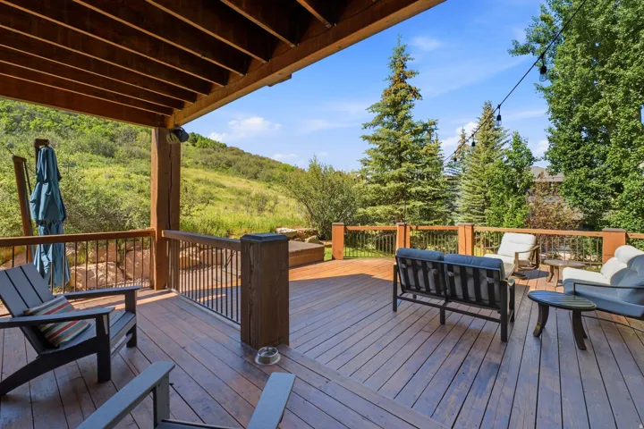 Spacious outdoor deck featuring wood-finish flooring, sturdy wood pillars, and black metal railings