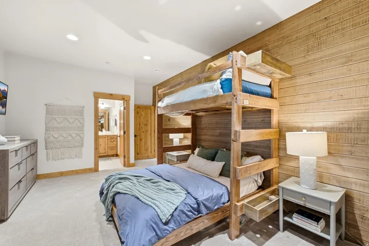 Wood-paneled accent wall in a carpeted room featuring a built-in bunk bed with integrated storage
