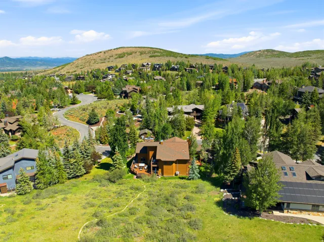 Rustic-style residence featuring a multi-level deck and surrounding mature trees