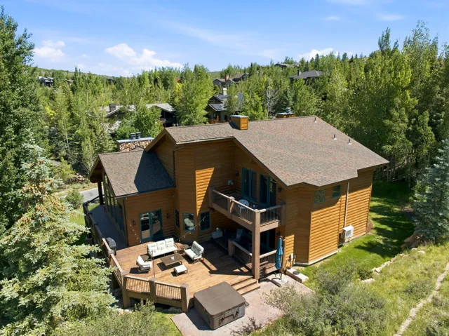 Multi-level wood-sided residence featuring a spacious outdoor deck, integrated hot tub, and a second-story balcony