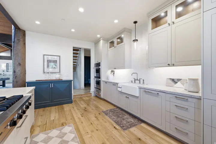 Modern kitchen featuring light wood-finish flooring, light grey cabinetry, and integrated double ovens