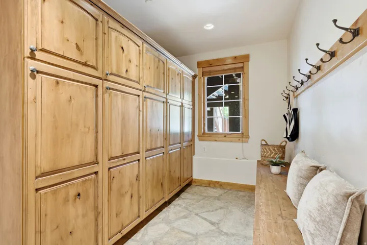 Built-in wood cabinetry providing extensive storage, complemented by a distressed wood bench and coordinating wood trim around the window and along the wall