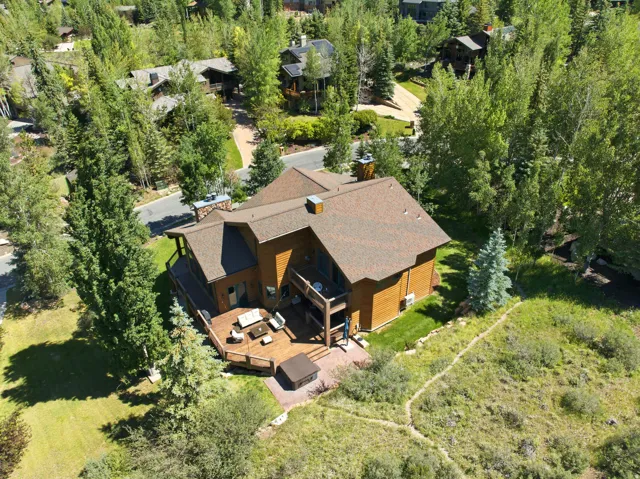 Wood-sided residence featuring a multi-level deck, a shingle roof, and multiple chimneys