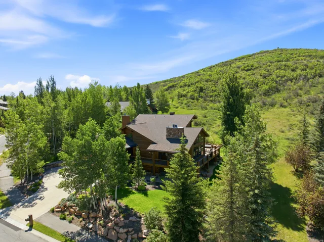 Wood-sided residence with multiple outdoor deck areas, a prominent stone chimney, and a brown shingle roof