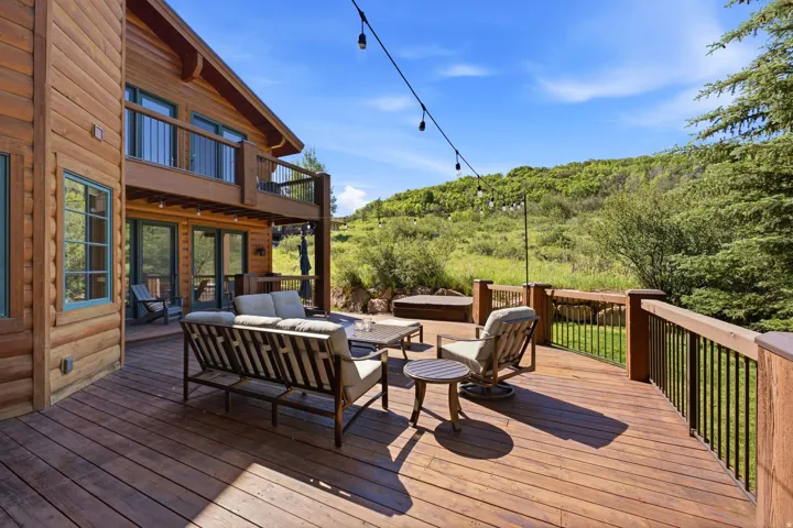 Expansive multi-level wood deck featuring a built-in spa, dark metal railings, and string lighting