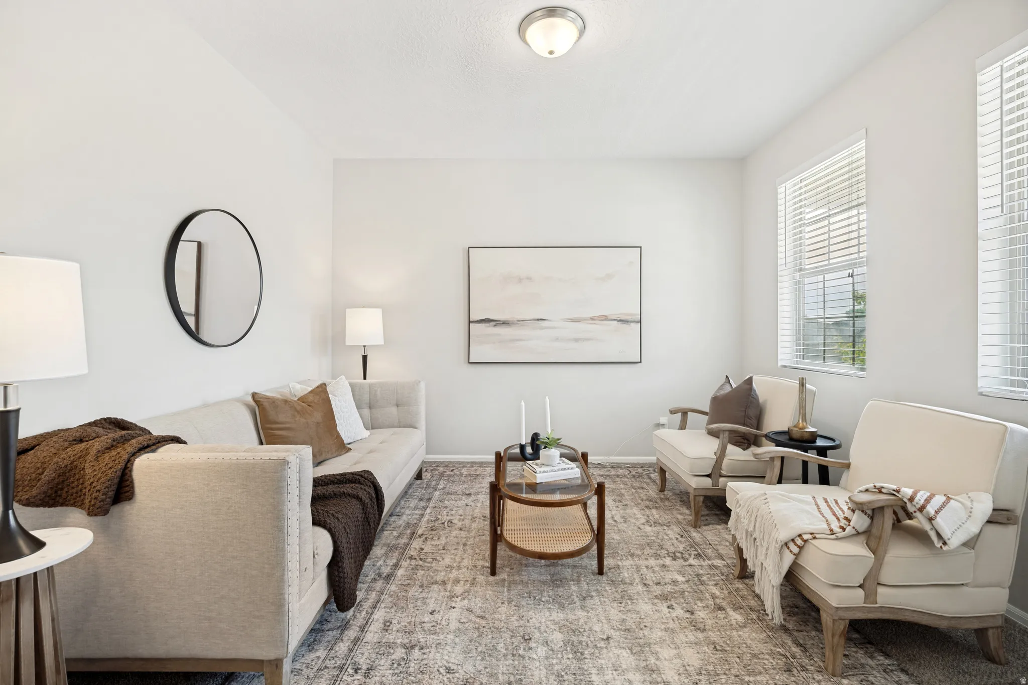 Bright living space featuring a flush-mount ceiling light fixture, two windows with blinds, and light-toned wall finishes