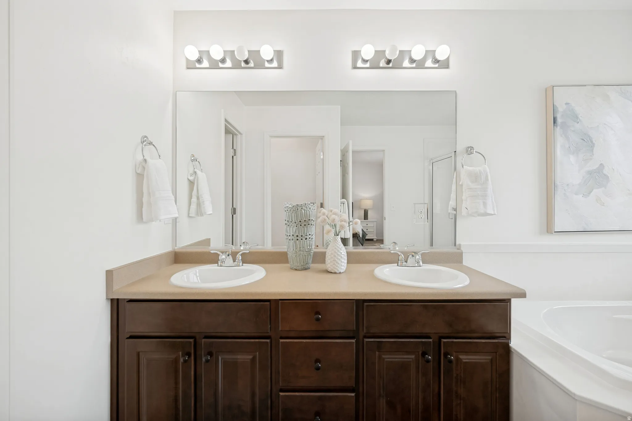 Double vanity with integrated sinks, dark wood-finish cabinetry, and a light-toned countertop