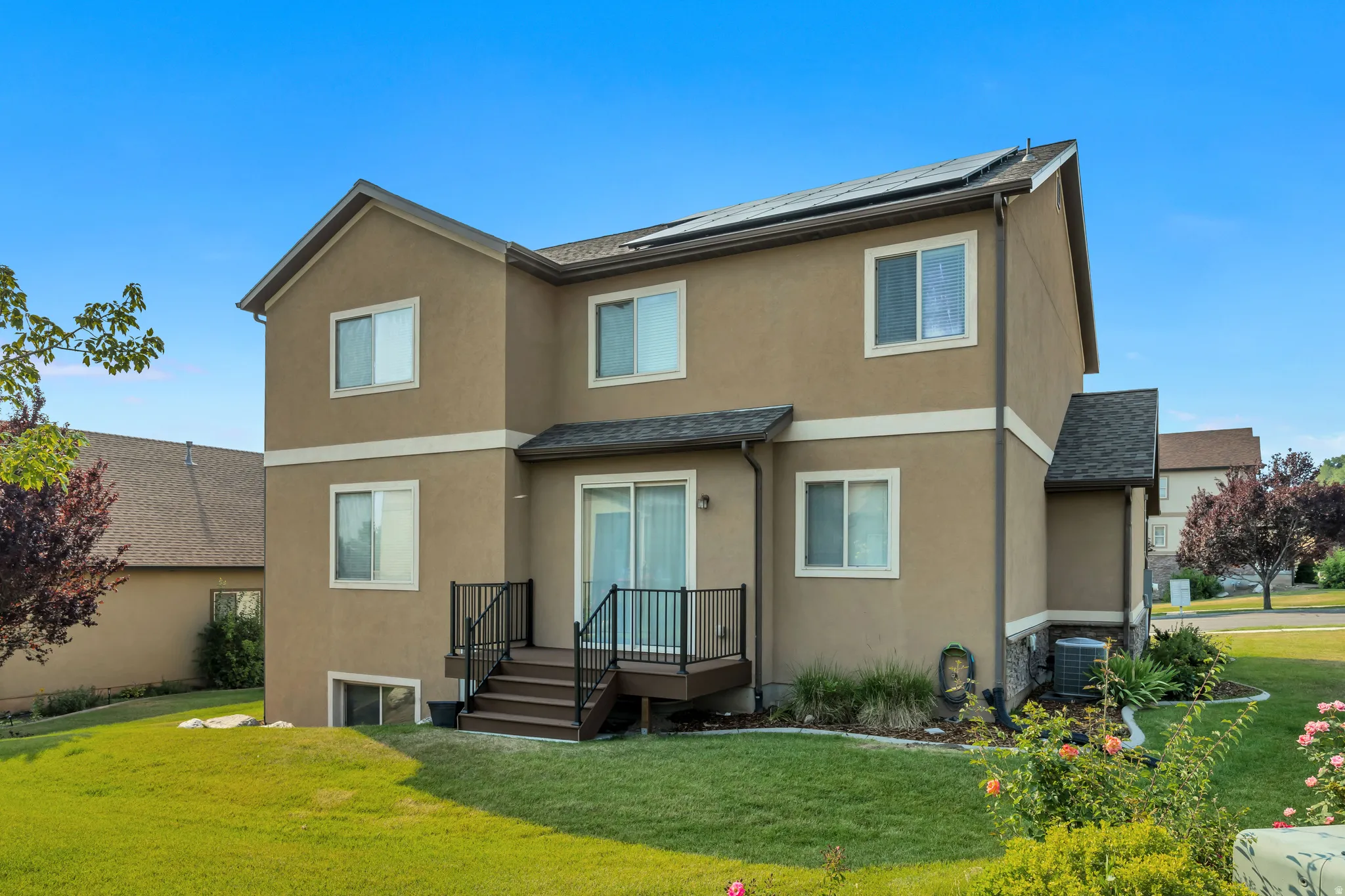 Rear exterior showcasing a multi-level design with a stucco finish and white window trim